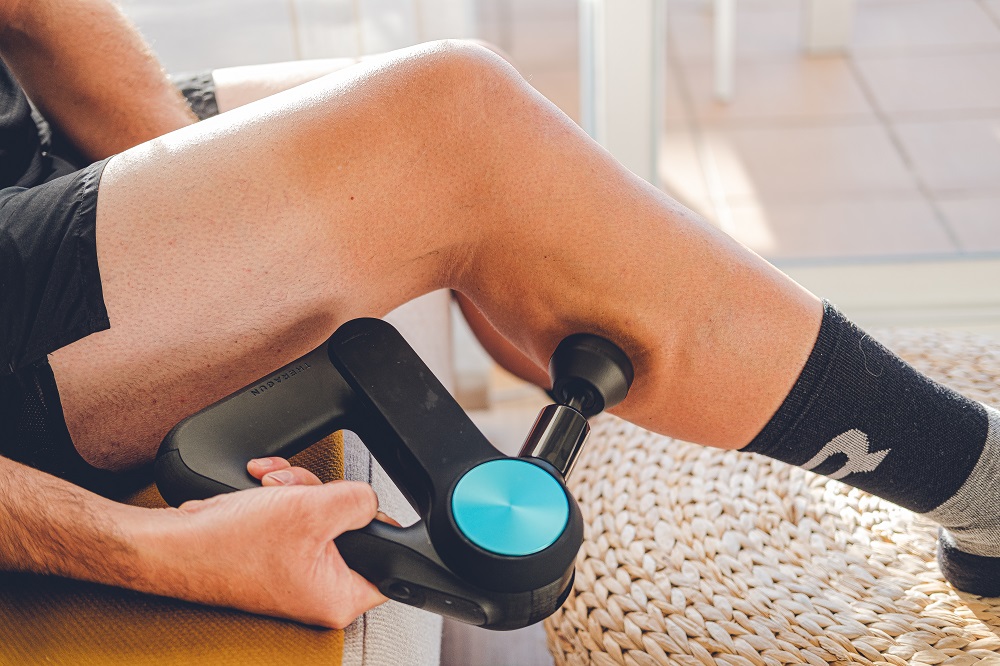 Coureur utilisant un pistolet de massage sur le mollet après une séance de course à pied