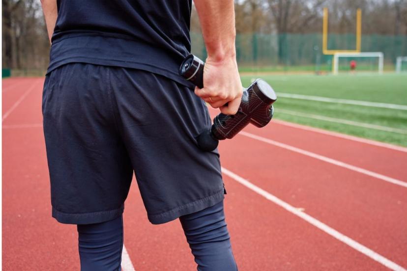 Utilisation d'un pistolet de massage en échauffement avant une séance de sport